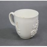 An 18th century white-glazed coffee cup with applied sprigs of prunus blossom, 2¼” high; possibly