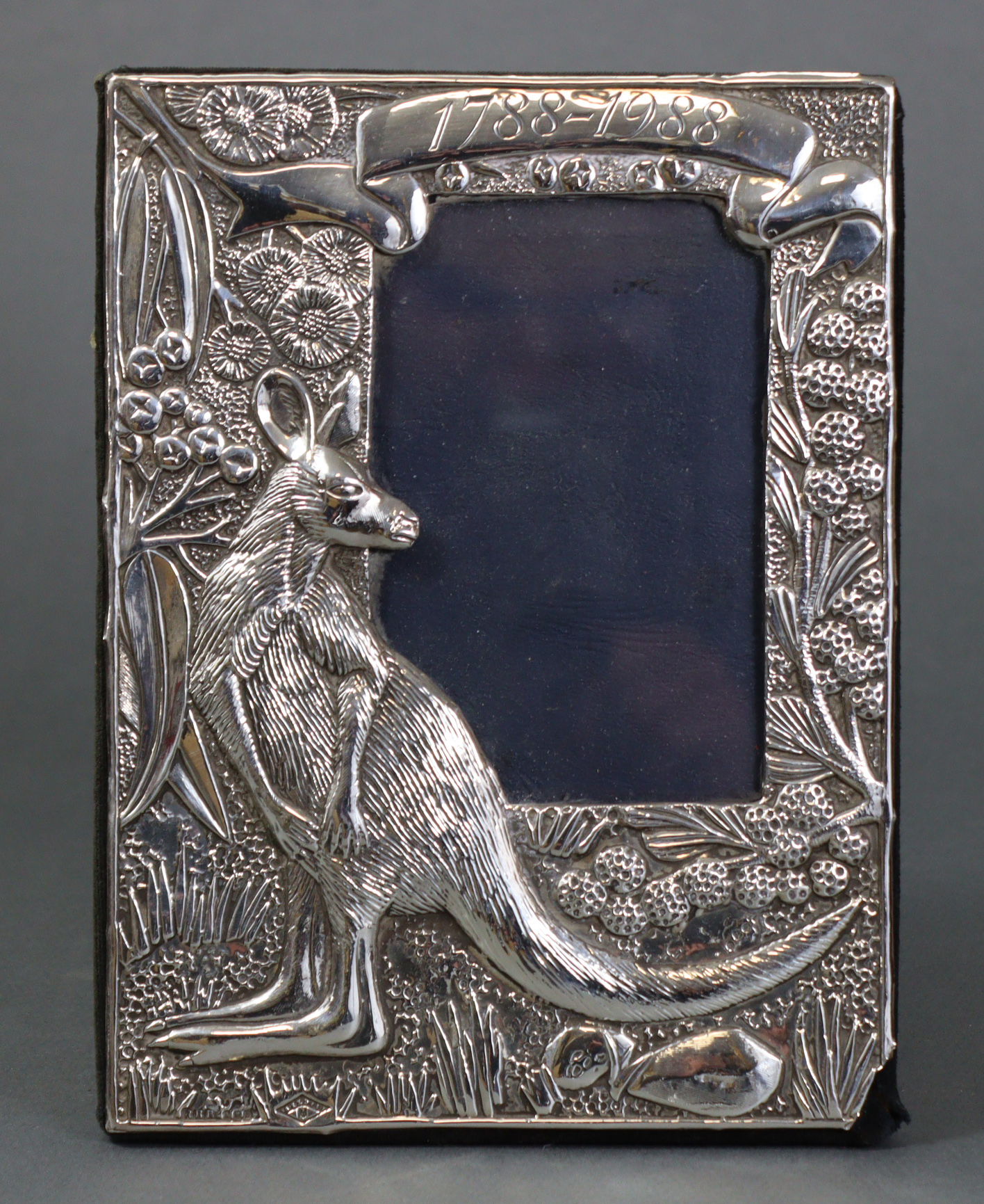 A rectangular commemorative silver photograph frame with embossed decoration depicting a kangaroo