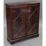 A mahogany bookcase with two adjustable shelves enclosed by pair of glazed doors, & on bracket feet,