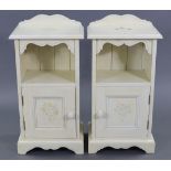 A pair of white & floral painted pine bedside cabinets each with open recess above a cupboard