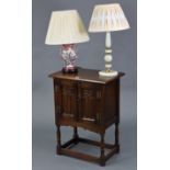 A reproduction oak bedside cabinet enclosed by pair of panel doors, & on baluster-turned supports