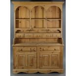 A PINE DRESSER the upper part fitted with an arrangement of open shelves & five small drawers, the