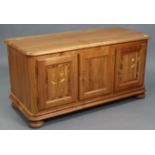 A pine & light oak blanket box enclosed by hinged lift-lid & three panel doors, & on bun feet,