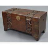 A Chinese camphor wood trunk with carved banded foliate decoration to the hinged lift-lid, front &
