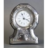 An Edwardian mantel timepiece, the silver mounted front embossed with roses & a ribbon-bow, 5” high;