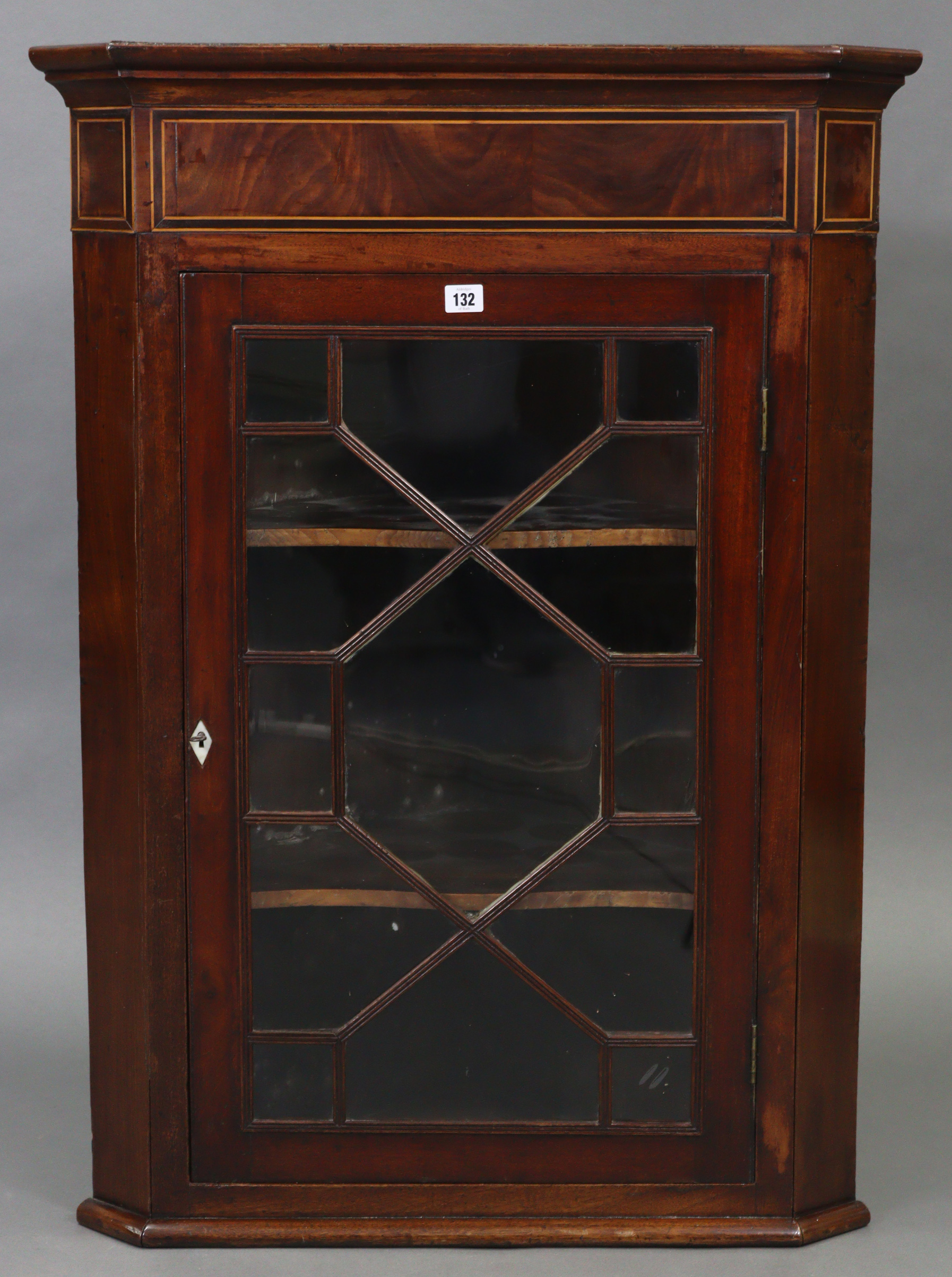 An early 19th century inlaid-mahogany hanging corner cabinet fitted two shaped shelves enclosed by a