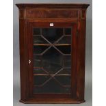 An early 19th century inlaid-mahogany hanging corner cabinet fitted two shaped shelves enclosed by a