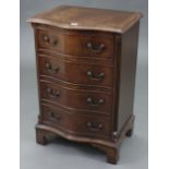 A reproduction mahogany-finish small serpentine-front chest, fitted four long drawers with brass