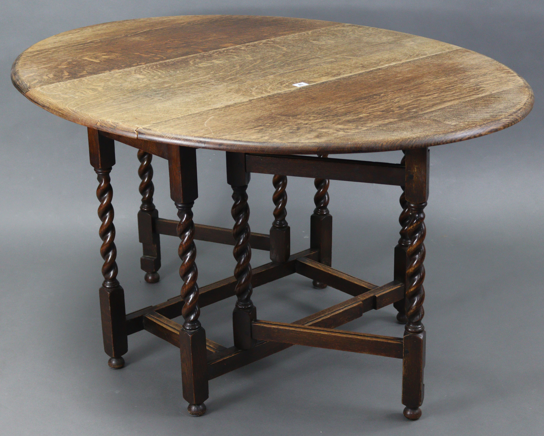 A 1930’s oak oval gate-leg dining table on barley-twist legs & turned feet with plain stretchers,