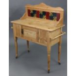 A small pine washstand, inset tiles to the stage back with cupboard enclosed by centre panel door, &