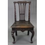 A late 19th/early 20th century carved oak splat-back hall chair with hard seat, & on cabriole legs &