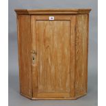 A pine small hanging corner cupboard, fitted two shelves enclosed by a panel door, 22” wide x 26½”
