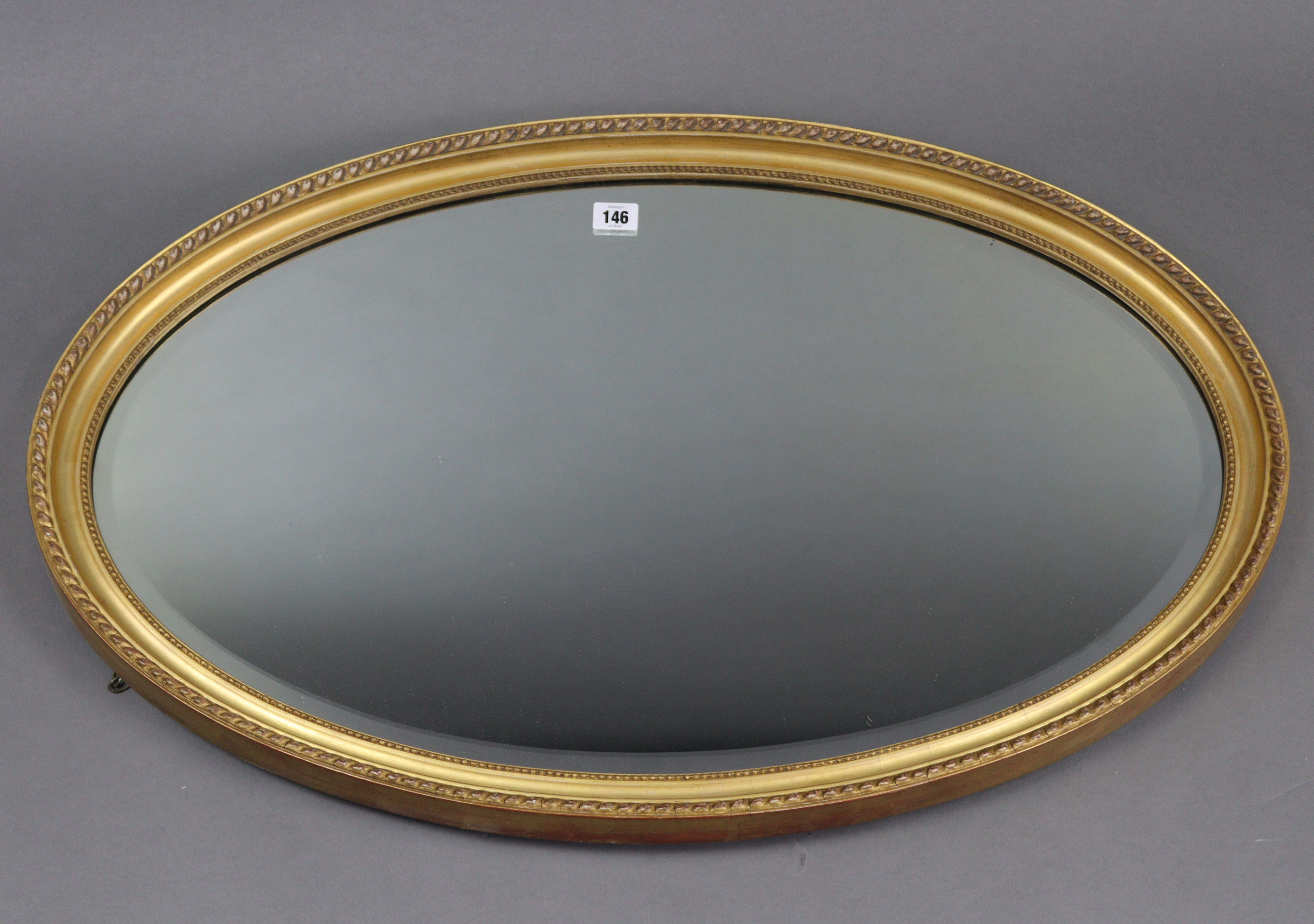 A gilt frame oval wall mirror with beaded edge & inset bevelled plate, 21” x 32½”.