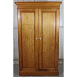A Victorian pine wardrobe with moulded cornice, having fitted interior enclosed by pair of panel