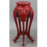 A Chinese-style red lacquered wooden jardinière stand with circular top, with pierced frieze, & on