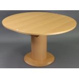 A maple-finish oval extending dining table with centre leaf, & on cylindrical centre column &