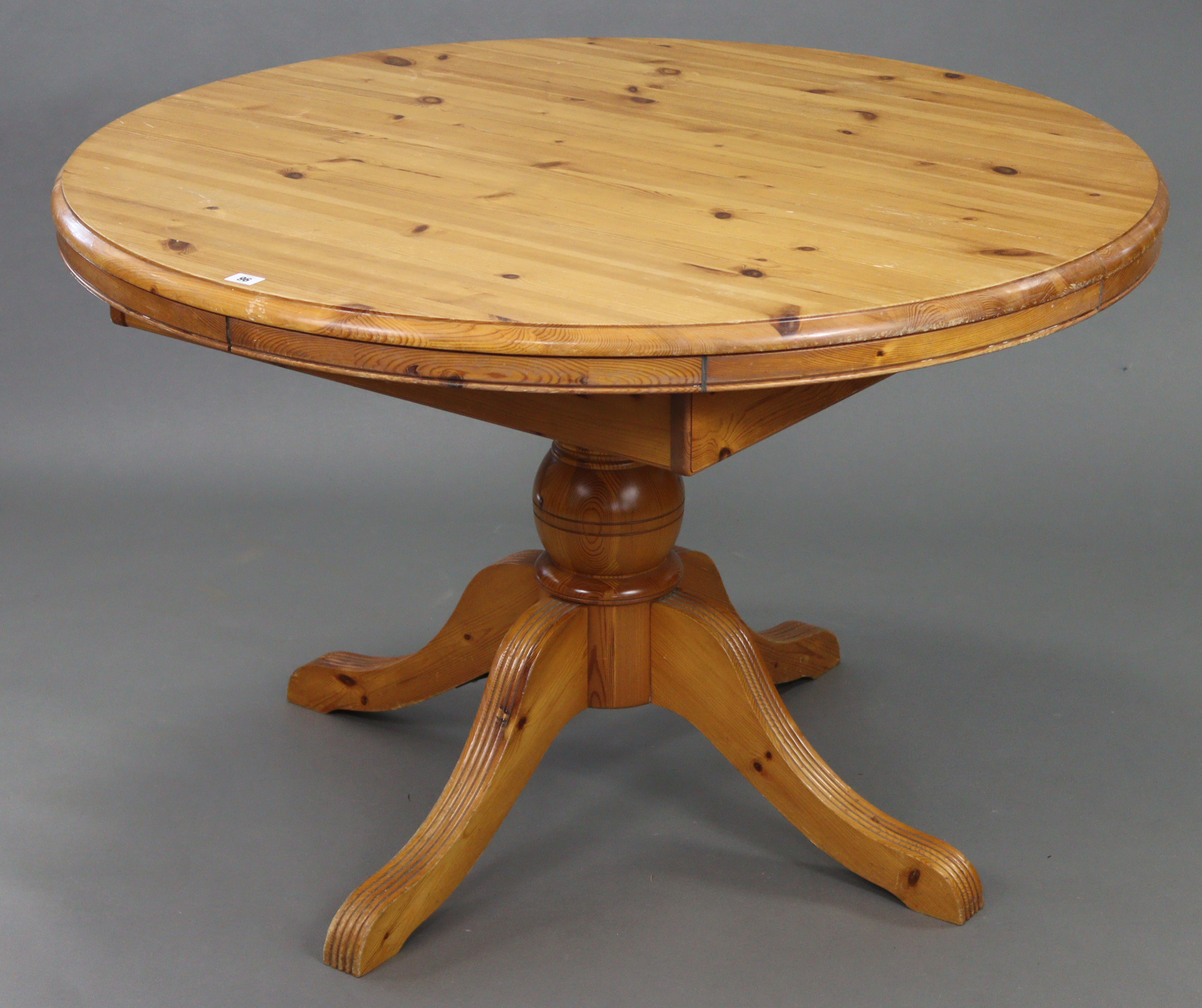 A pine circular extending pedestal dining table, with centre leaf & on vase-turned centre column &