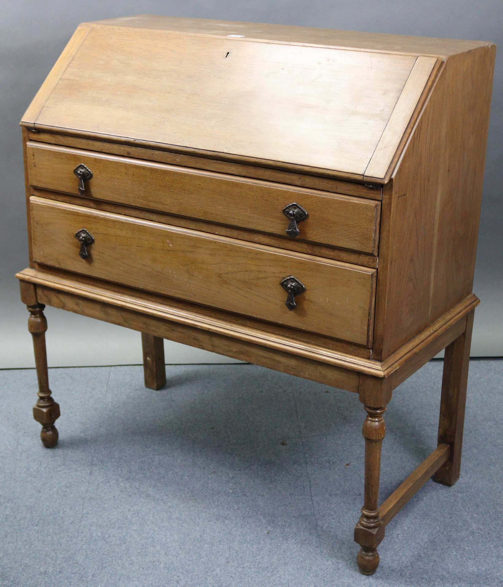 An early/mid-20th century oak bureau with fitted interior enclosed by fall-front above two long