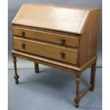 An early/mid-20th century oak bureau with fitted interior enclosed by fall-front above two long