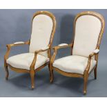 A pair of continental-style beech frame easy chairs with padded seats, backs, & open arms, & on