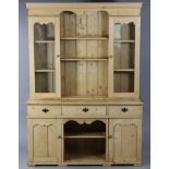 A late Victorian pine dresser, the upper part with shaped cornice above two glazed panel doors &
