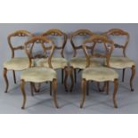 A set of six mid-Victorian walnut dining chairs with carved & pierced balloon-backs, the padded