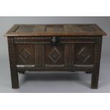 A 17th/18th century joined oak coffer with carved three panel front, panelled sides & hinged lid, on