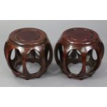 A pair of Chinese hardwood barrel-shaped stools with pierced sides, each on eight short bracket