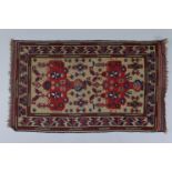 An Afghan small rug of fawn ground, the central panel with repeating flower design, within