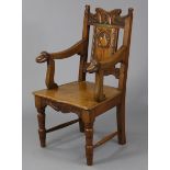 An Arts & Crafts oak armchair with carved stylised foliate decoration to the shaped backed,