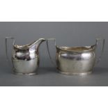 A George III silver milk jug of ovoid shape with angular handle & engraved foliate-scroll