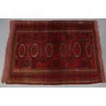 A Bokhara rug of crimson ground with central row of six lozenges in deep blue & ivory, with in