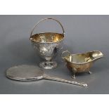 A Victorian silver sugar bowl with embossed floral decoration, swing handle & round pedestal foot,