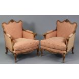 A pair of mid-Victorian carved mahogany frame armchairs with shell surmounts to the shaped padded