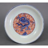 A Chinese porcelain shallow bowl decorated in underglaze blue & copper red with dragons amongst
