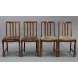 A set of four mid-20th century oak rail-back dining chairs with padded drop-in-seats; & on turned