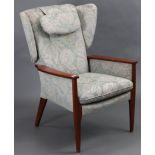 A Parker Knoll buttoned-back armchair upholstered green & white foliate material & on short square