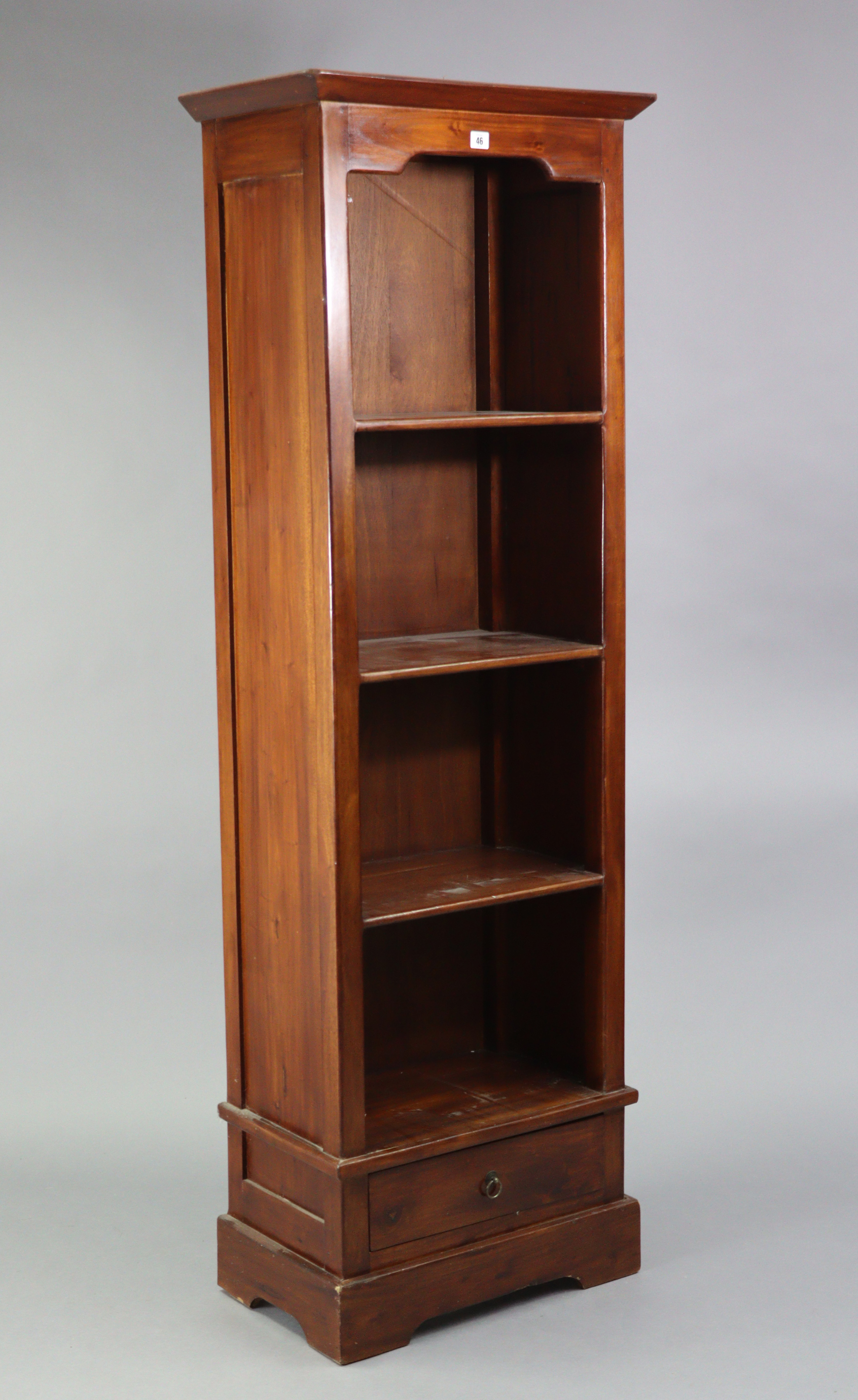 A hardwood tall narrow standing open bookcase fitted three shelves above a long drawer, & on a