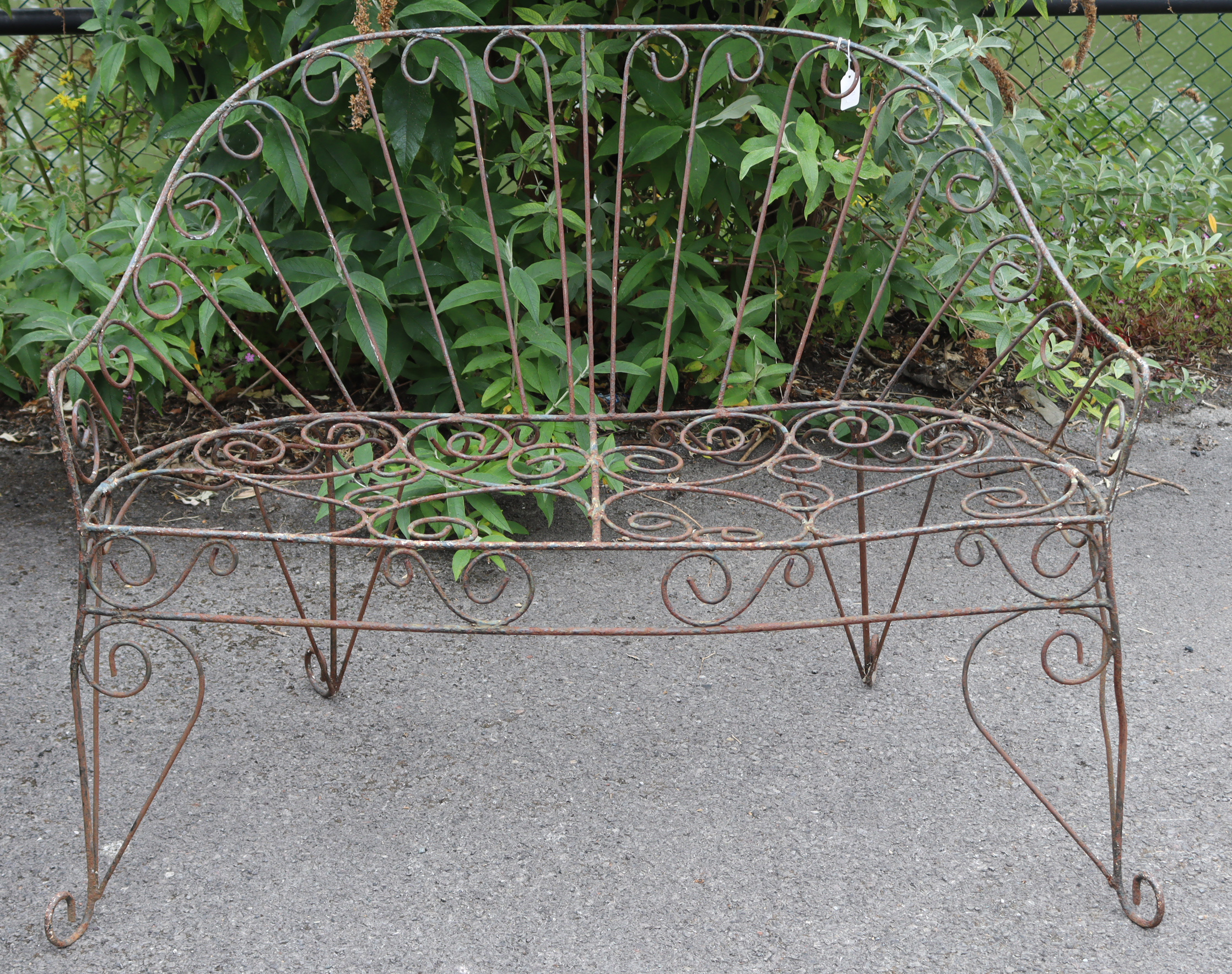 A Victorian-style wrought-iron two-seater garden bench with pierced scroll decoration, & on shaped
