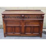 An oak sideboard, fitted two frieze drawers with carved fronts above cupboard enclosed by pair of