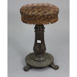 A late 19th century mahogany piano stool with padded revolving circular seat, & on a carved centre