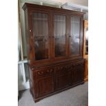 A dark oak tall dresser the upper part with two adjustable shelves enclosed by three glazed doors,