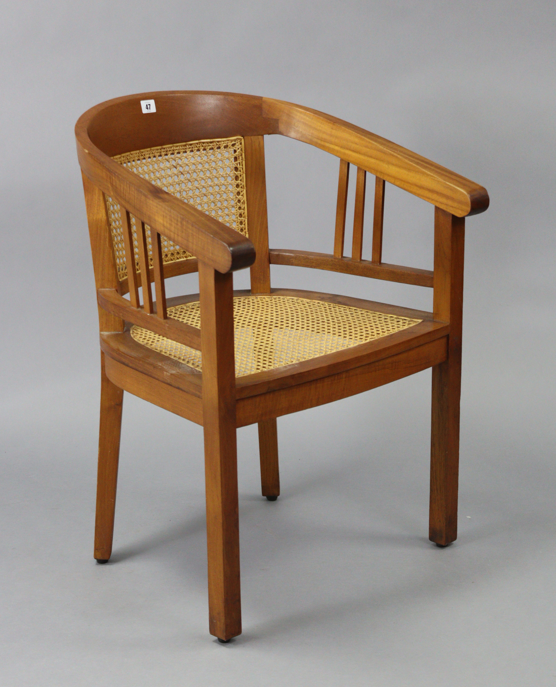 A teak tub-shaped chair inset woven-cane panel to the seat & back, & on square tapered legs.