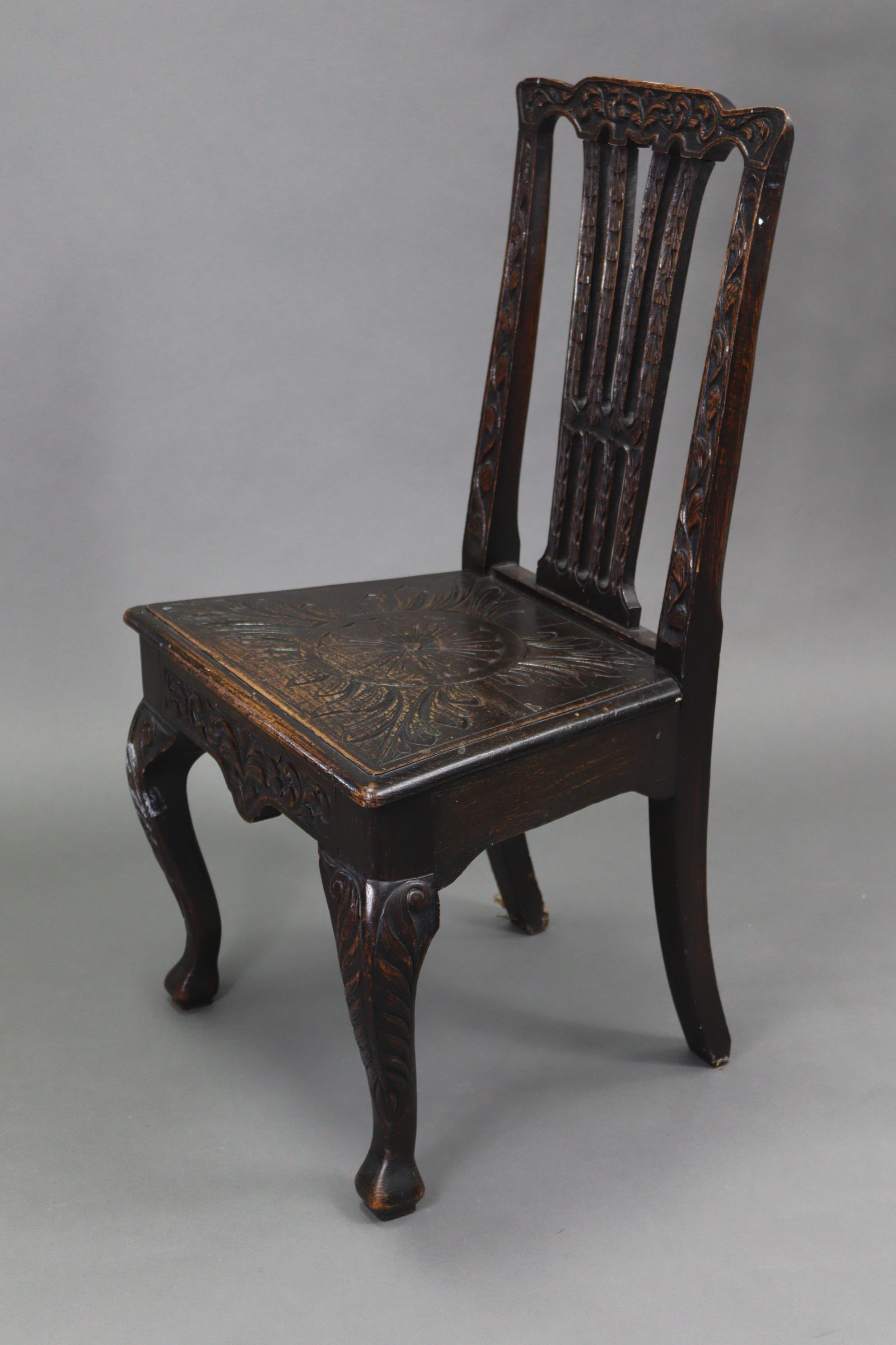 A late 19th/early 20th century carved oak splat-back hall chair with hard seat, & on cabriole legs &