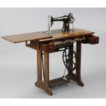 A Singer treadle sewing machine in walnut case, 34” wide x 30½” high.