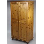A modern pine wardrobe enclosed by pair of fielded panel doors, & on bun feet, 37” wide x 72” high x