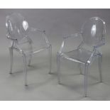 A pair of contemporary clear plastic elbow dining chairs on square tapered legs.