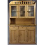A pine dresser, the upper part with pierced stage back & sides, fitted centre shelf enclosed by
