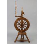 A 17” diam. wooden spinning wheel on three short turned legs, 39” high.