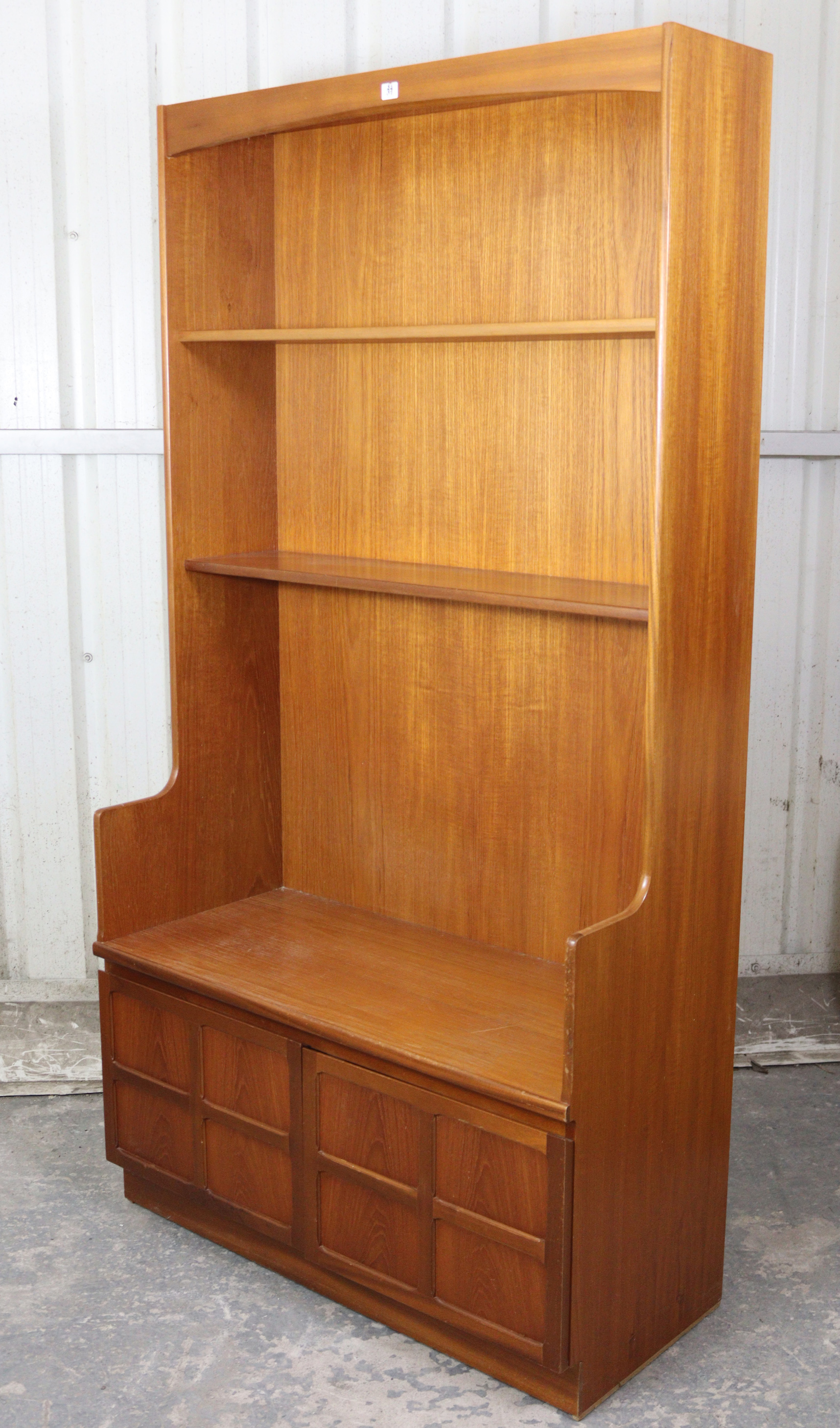 A Nathan teak tall wall unit fitted two shelves above cupboard enclosed by a pair of panel doors,